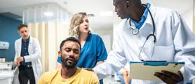 A doctor standing next to a seated patient