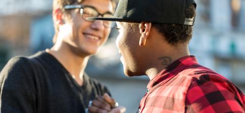 two smiling young men greeting each other