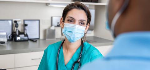 A masked doctor engaged in conversation 