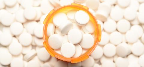 A prescription medication bottle overflowing with round white pills